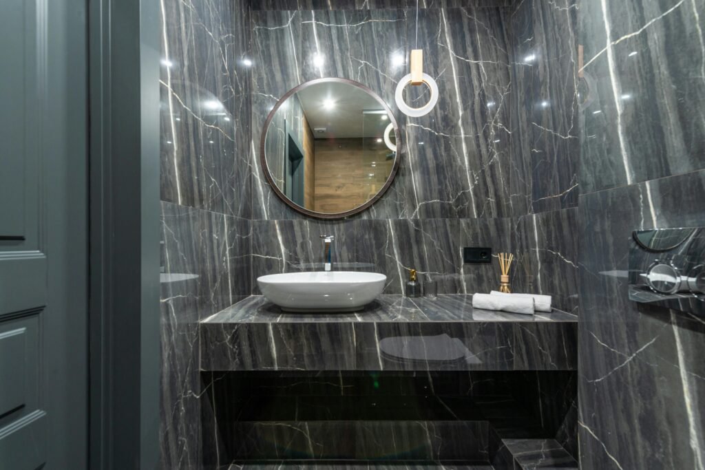 Contemporary bathroom design with marble surfaces and round mirror.